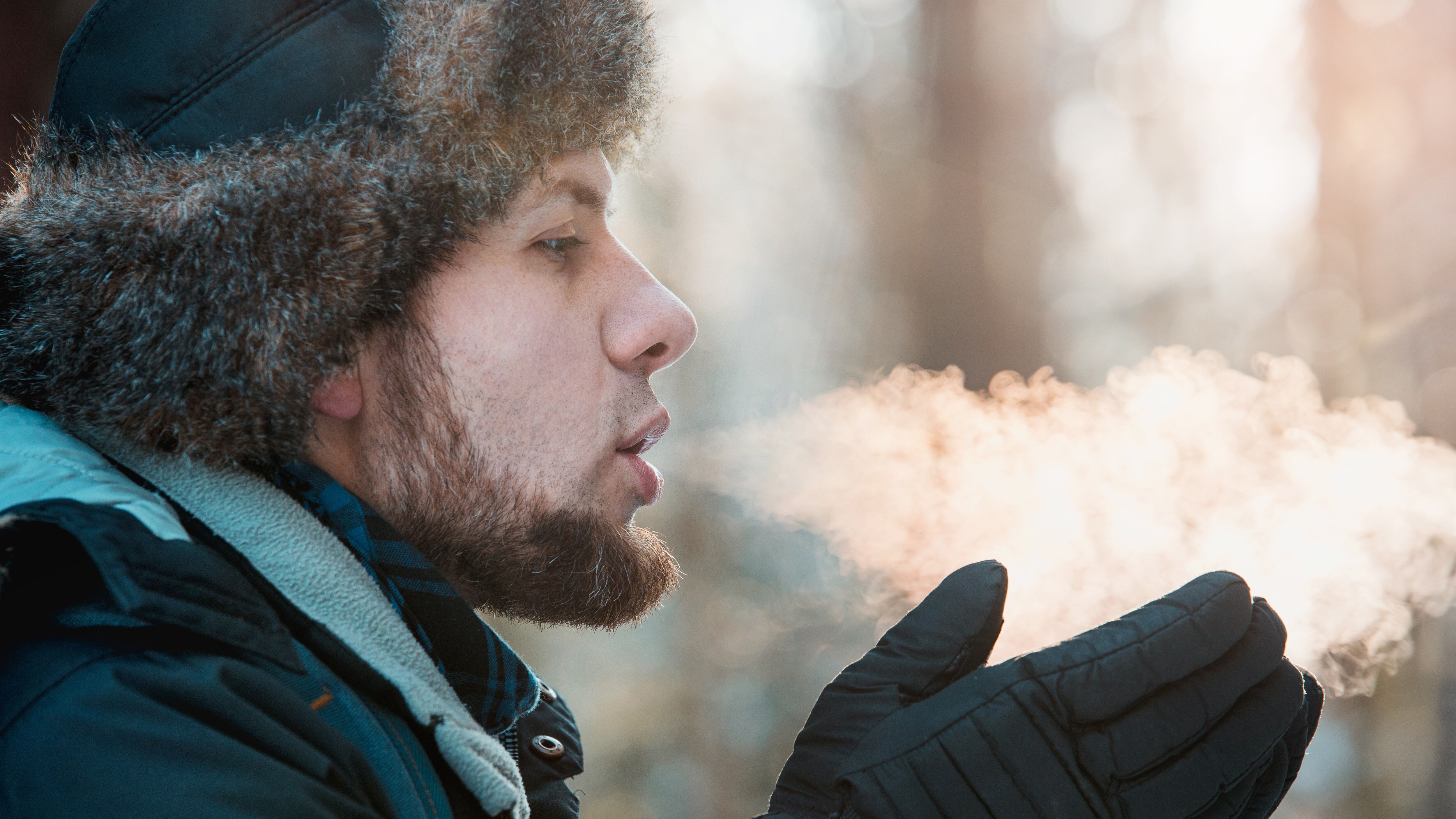 A man blowing air on gloves during the winter.